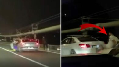 رجل فوق غطاء سيارة يدفع المركبة أمامه بقدميه على جسر إسطنبول