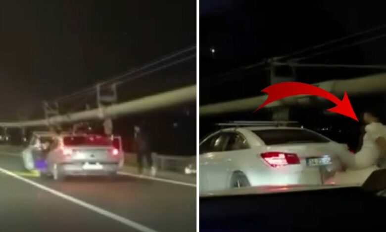 رجل فوق غطاء سيارة يدفع المركبة أمامه بقدميه على جسر إسطنبول